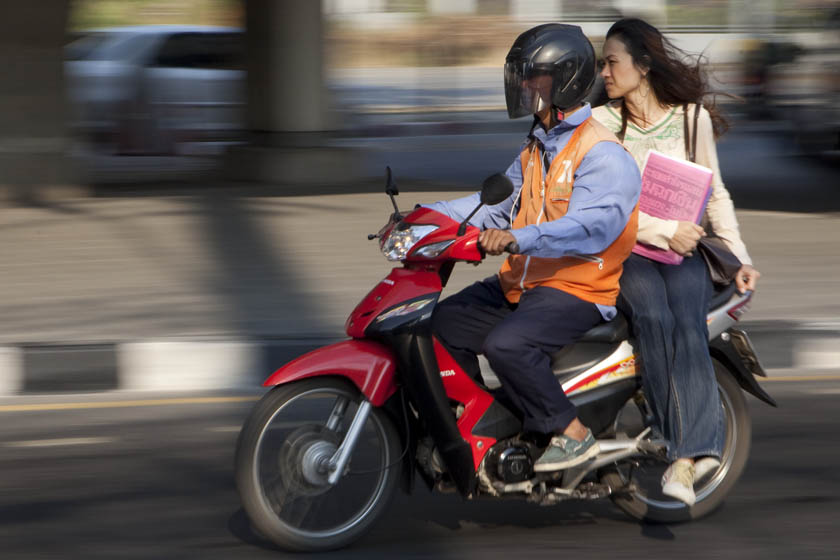 girl on Bangkok motorcycle taxi going to class